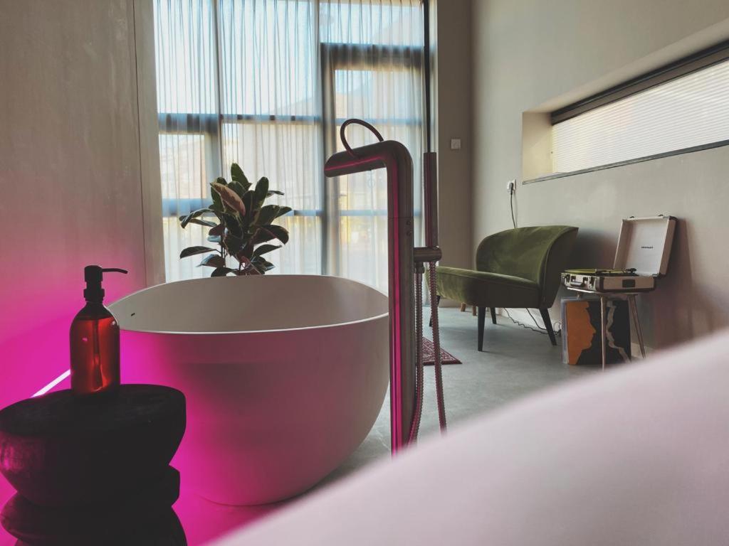 阿纳姆Home8 studio’s的浴缸位于粉红色灯的房间内