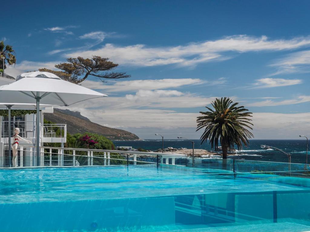 开普敦South Beach Camps Bay Boutique Hotel的一个带遮阳伞的游泳池以及大海