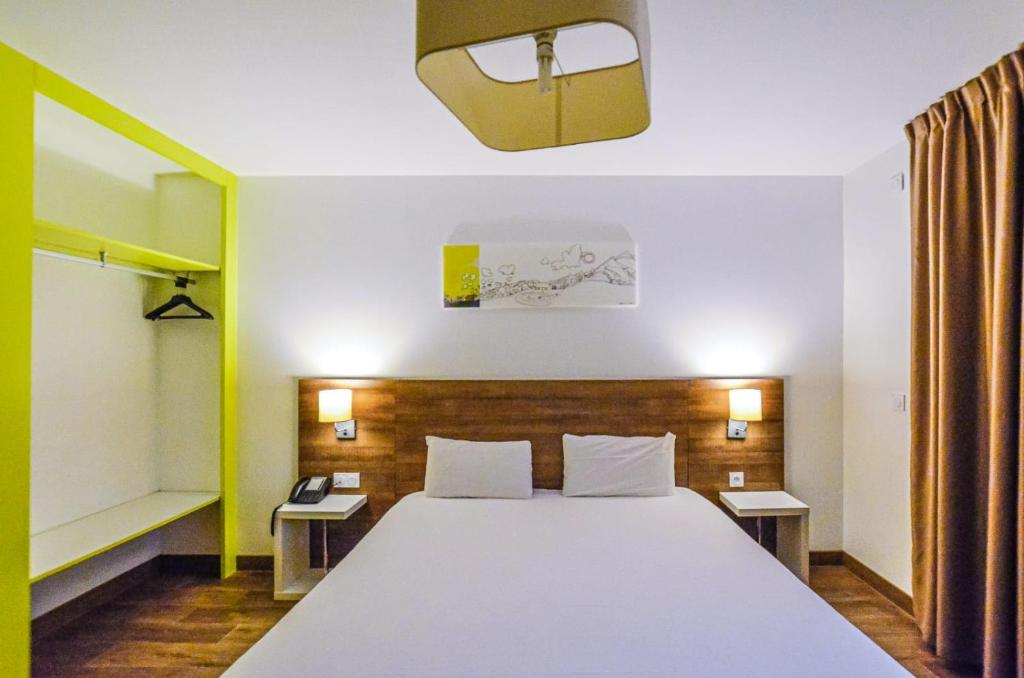 圣马丹代雷The Originals Résidence, Grenoble Université的卧室配有一张白色的大床和两张桌子