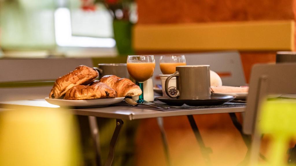 圣艾蒂安Hôtel Furania的一张桌子,上面放着一盘面包和一杯橙汁