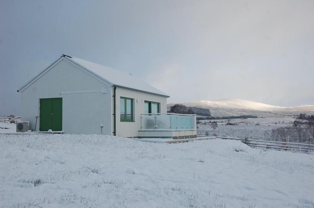 史宾桥Glas Beag的雪中带绿门的白色房子