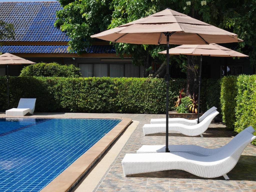 皮皮岛Andaman Resort的一个带2把躺椅和遮阳伞的游泳池