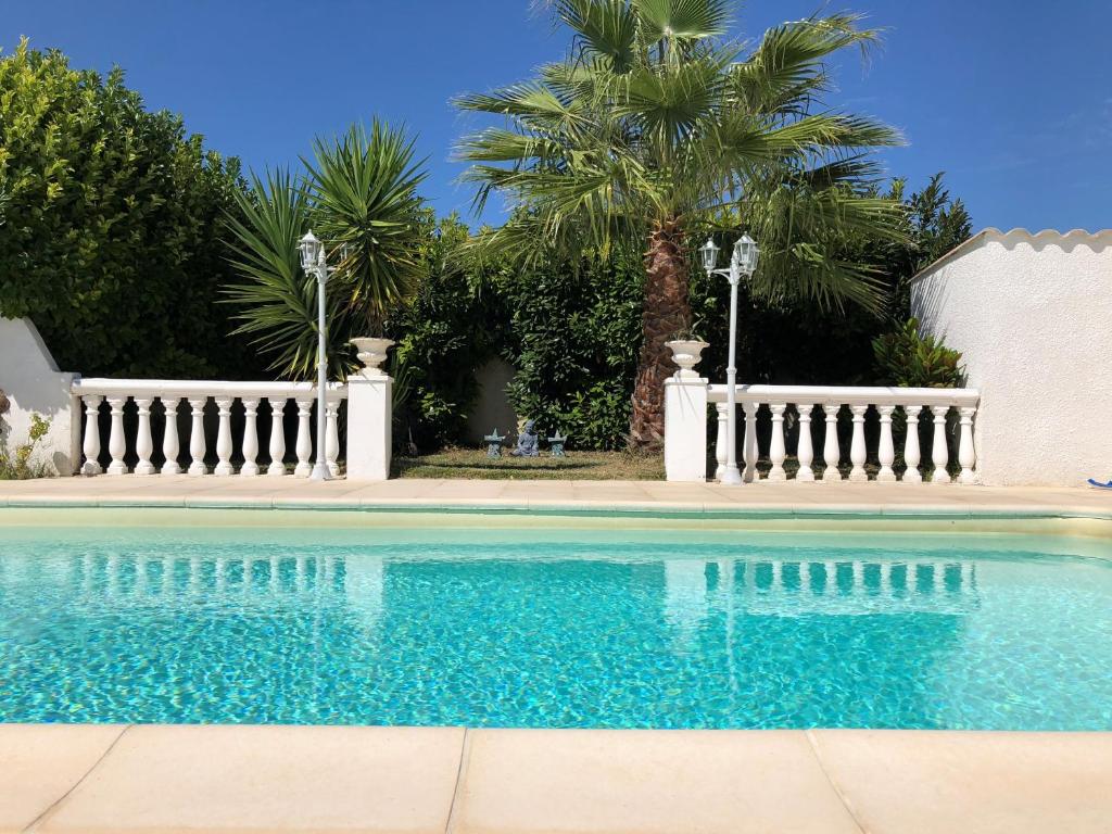 贝济耶Villa du sud ouest的一个带白色围栏和棕榈树的游泳池