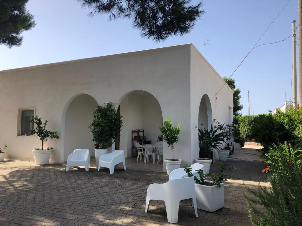 马鲁焦Villa Lucia的白色的建筑,有白色的椅子和盆栽植物