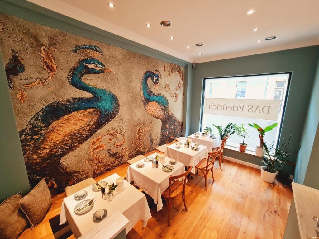 克尼特尔费尔德Das Friedrich的餐厅设有白色桌子和孔雀壁画