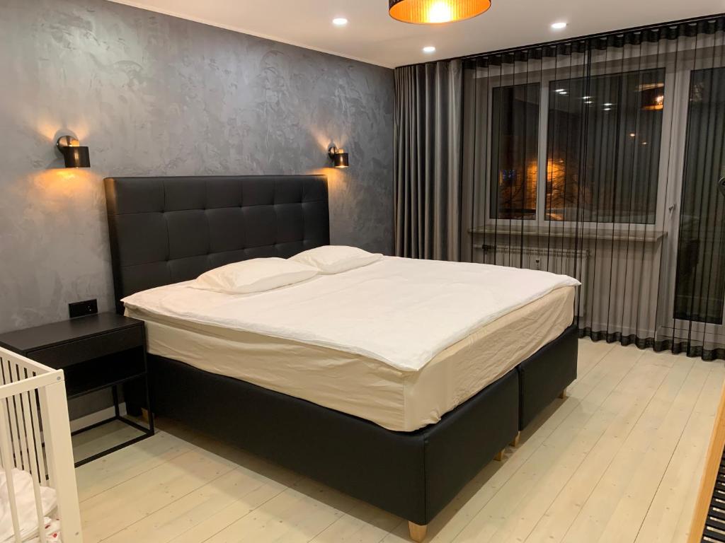 派尔努Tammsaare Luxury Apartment的一间卧室配有一张大床和黑色床头板