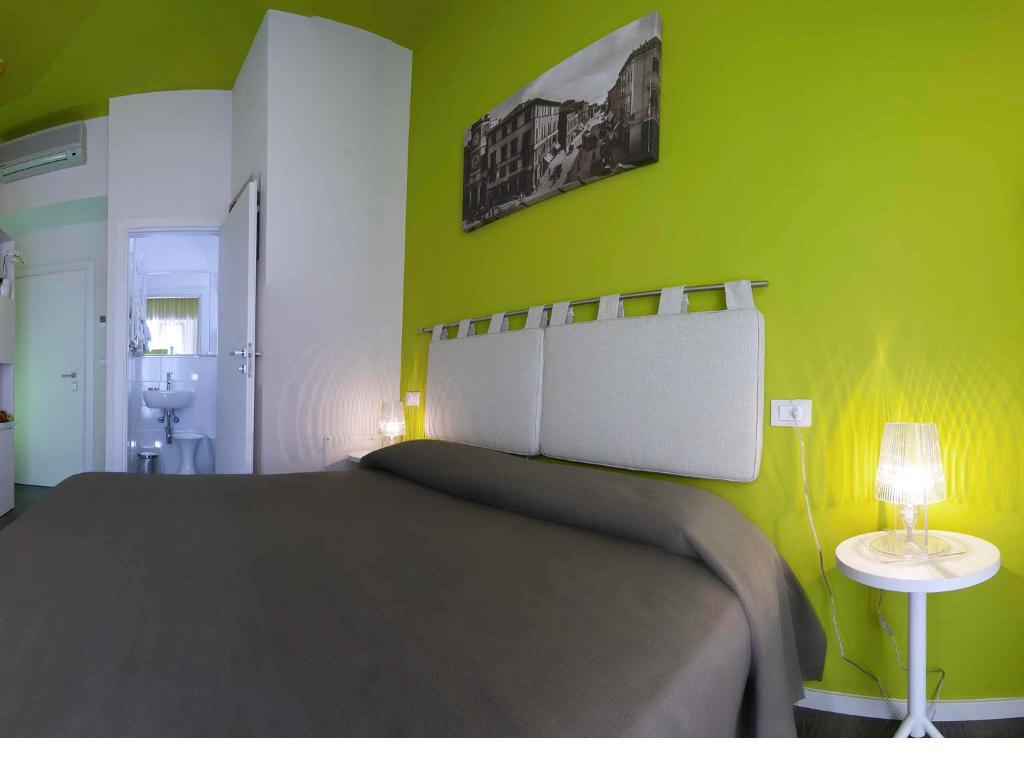 里米尼卡萨布兰卡酒店的一间卧室设有一张大床和绿色的墙壁