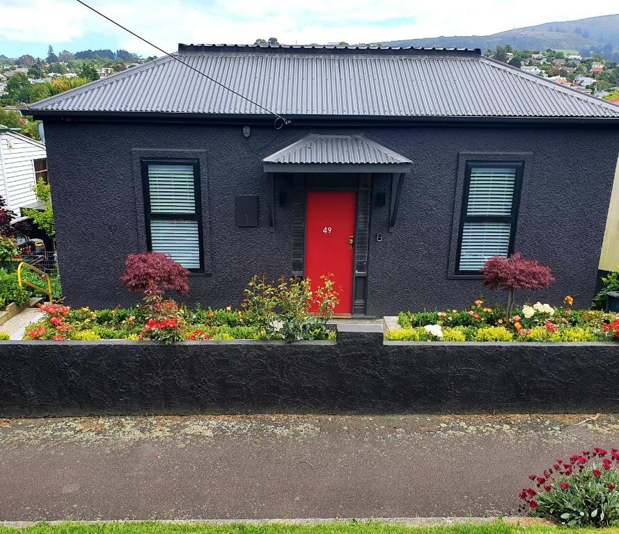 但尼丁Roslyn Business Studio - 2 bedroom的红门和花朵的黑色房子