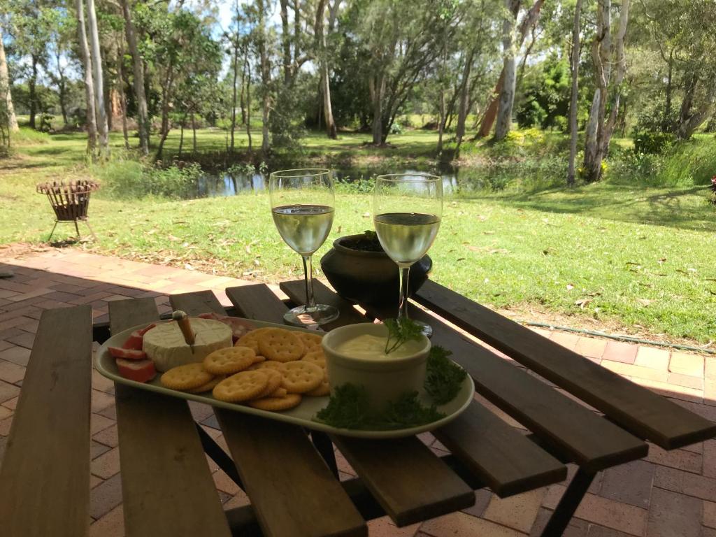 Weyba DownsNoosa Lake Weyba的野餐桌上放一盘食物和两杯葡萄酒