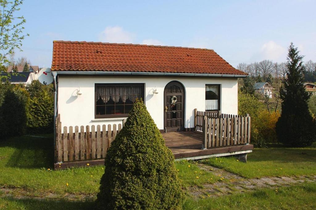Klein SprenzCottage, Dolgen am See的一座白色的小房子,在院子里设有木栅栏