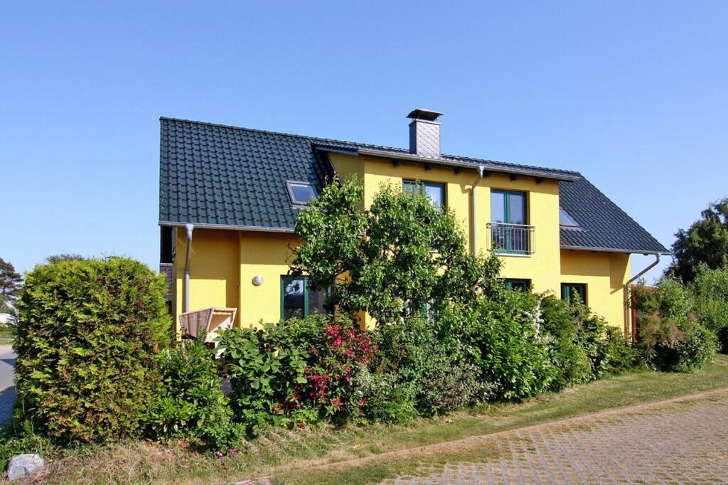 NeuendorfDoppelhaushälfte mit Blick auf das Wasser am Hafen von Neuendorf的前面有灌木的黄色房子