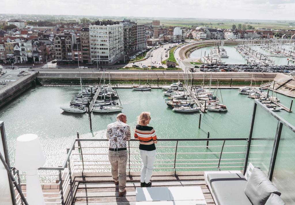 布兰肯贝赫ZEEPAREL Duplex loft的两人站在俯瞰着码头的阳台