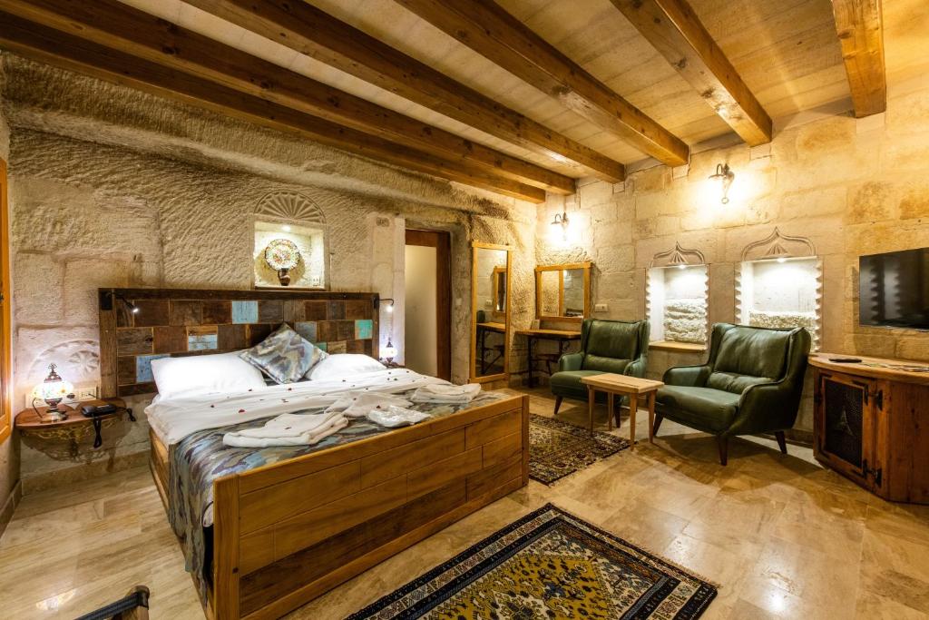 格雷梅Charming Cave Hotel的一间卧室,卧室内配有一张床和两把椅子