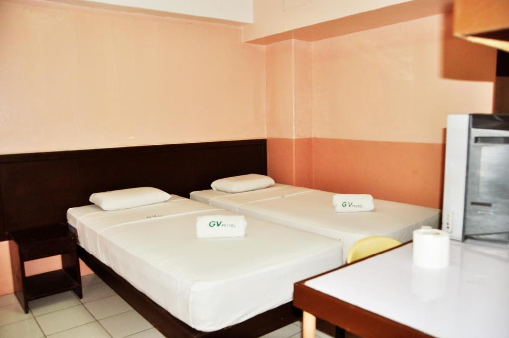 麦克坦拉普拉普城市GV酒店 的小型客房配有两张床和一张桌子。