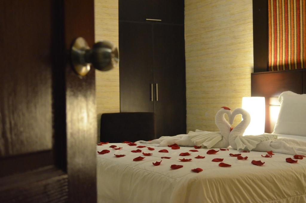 利马秘鲁蒙特瑞科酒店的两个天鹅坐在床上,床上有玫瑰花