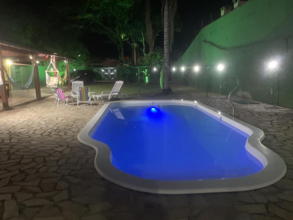 伊塔蒂亚亚Casa de Campo em Penedo - RJ的夜晚在院子里的一个蓝色游泳池