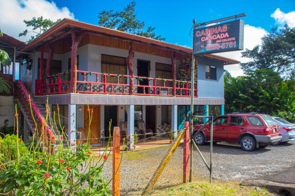 比加瓜Cabinas Cascada Rio Celeste的前面有一辆红色汽车的建筑