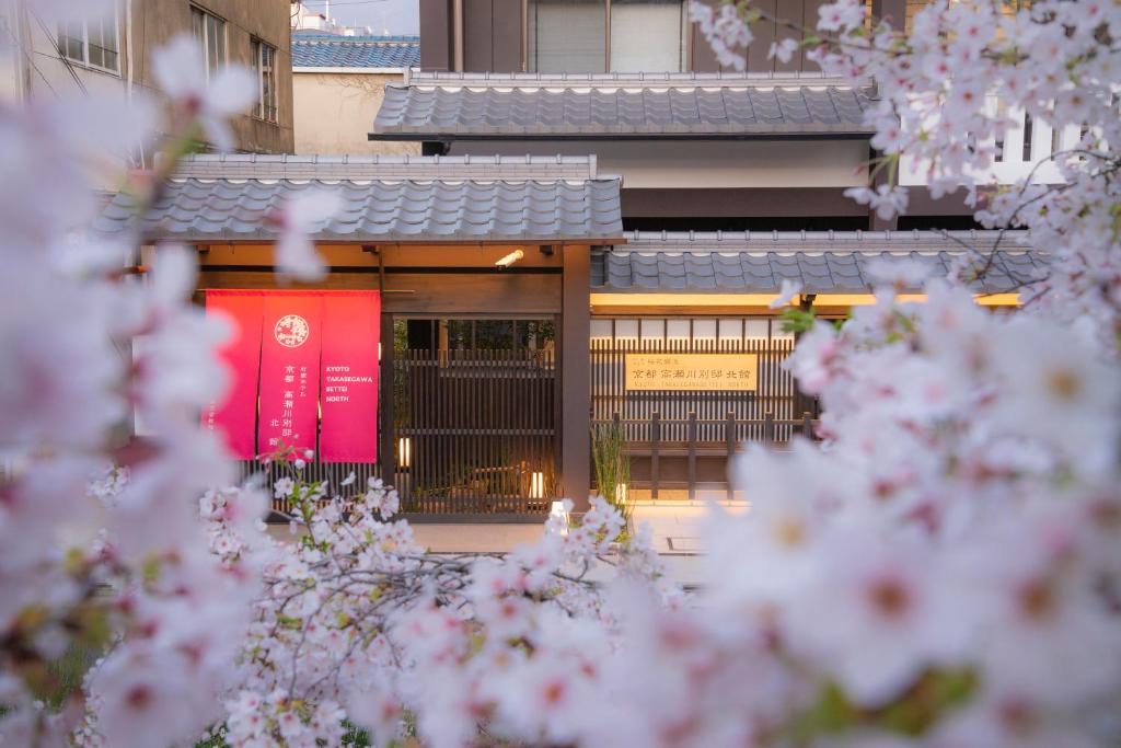 京都京都高濑川别邸的前方有红色标志的建筑,有粉红色的花朵