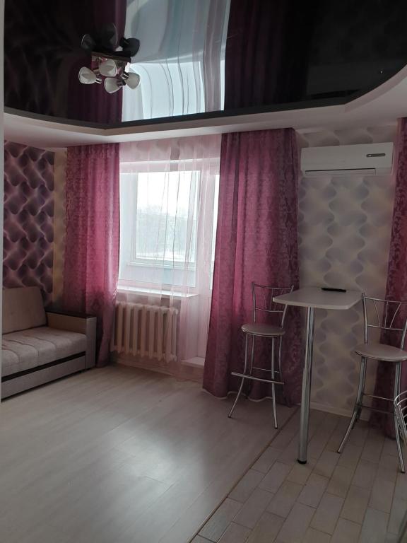 乌里扬诺夫斯克Симбирские апартаменты на Варейкиса 42的客厅配有粉红色的窗帘和桌椅