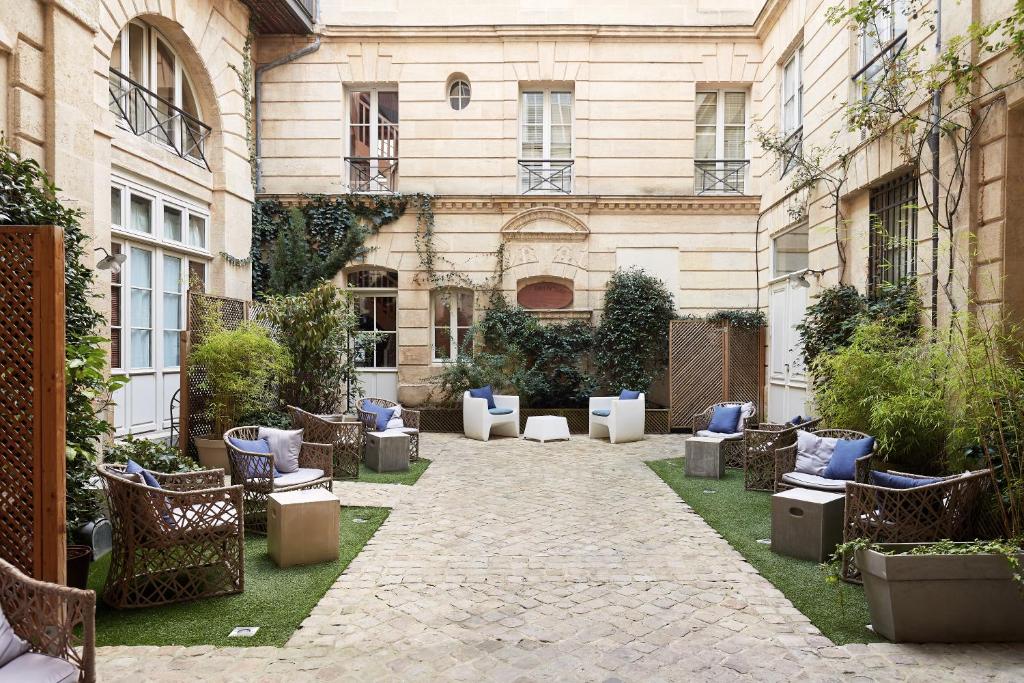 波尔多L'Apparthôtel Particulier Bordeaux的一座带蓝色枕头和椅子的建筑的庭院