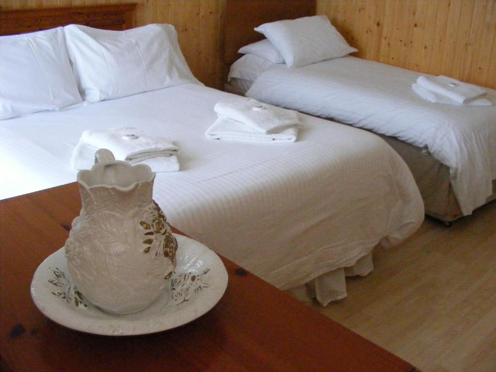 道格拉斯特里维廉住宿加早餐旅馆的两张带白色床单和桌子花瓶的床