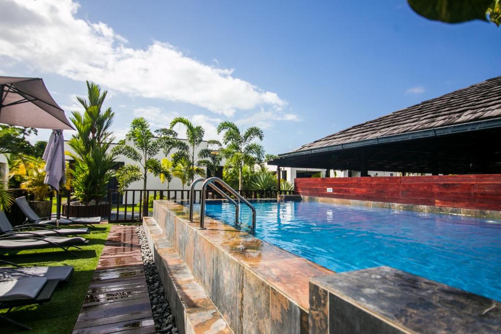 帕拉马里博Bronbella Villa Residence的度假村的游泳池配有椅子和遮阳伞