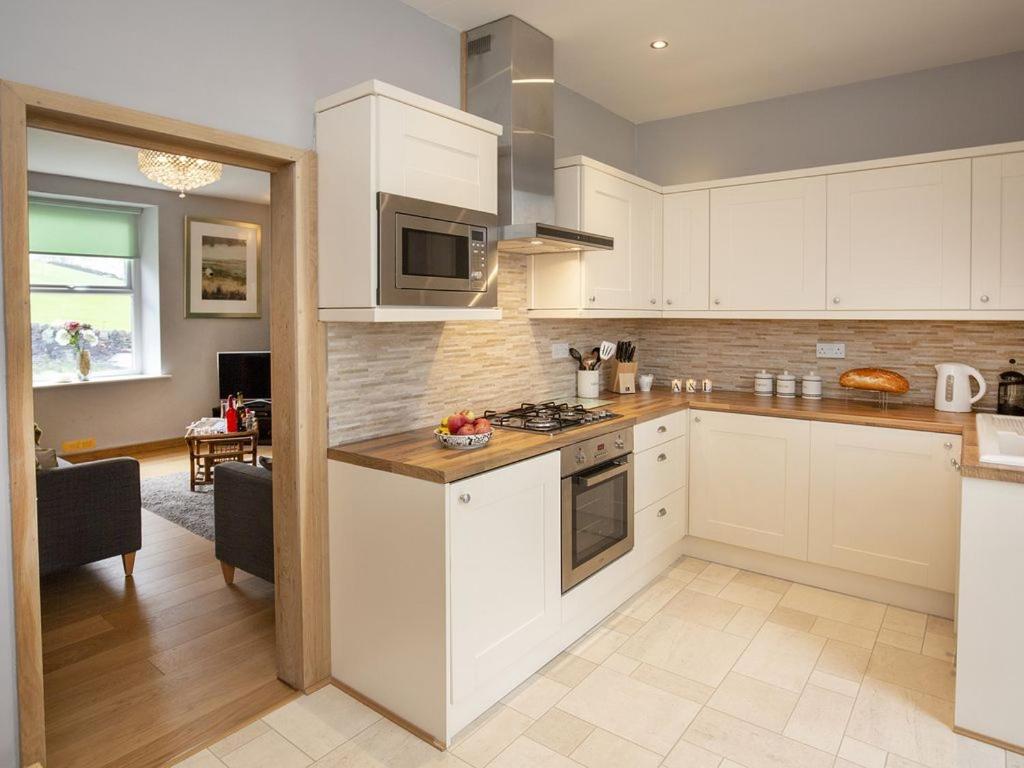 哈沃斯The Yorkshire Hosts - Fall in Green Cottage的厨房配有白色橱柜和炉灶烤箱。