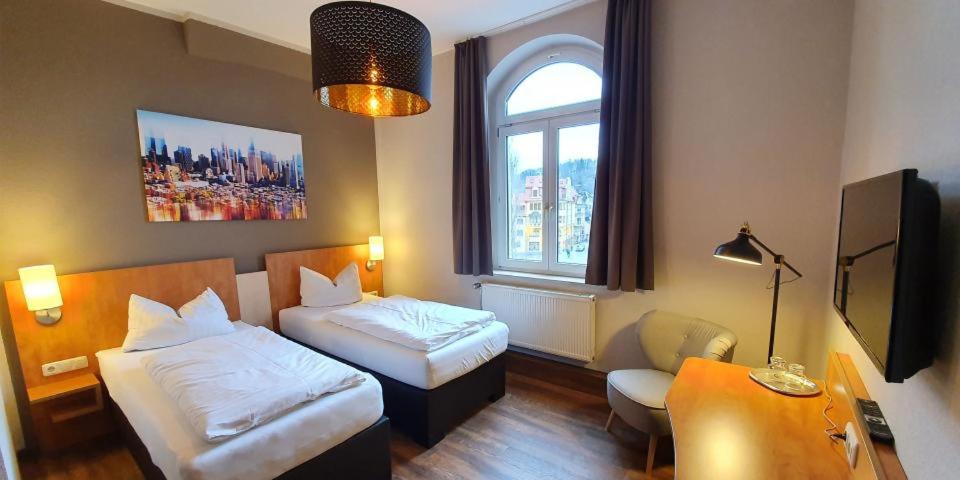 格赖茨Hotel Friedensbruecke的酒店客房设有两张床、一张书桌和一个窗户。