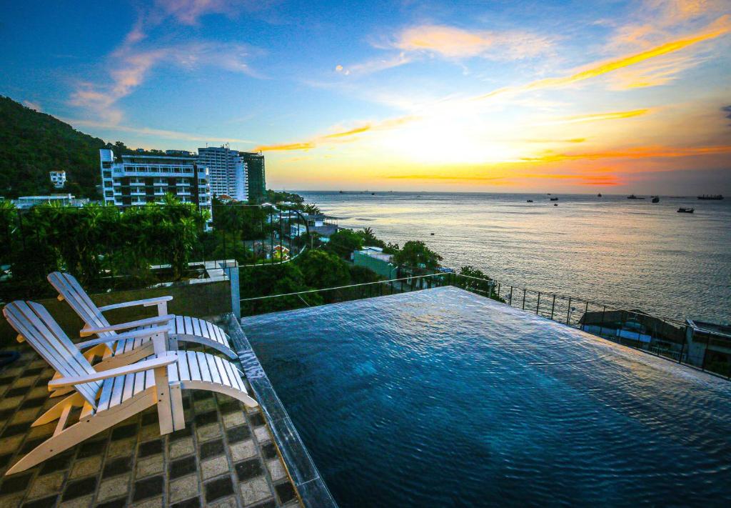 头顿Fati Boutique Hotel & Apartment的一个带两把椅子的游泳池,日落时分享有海景