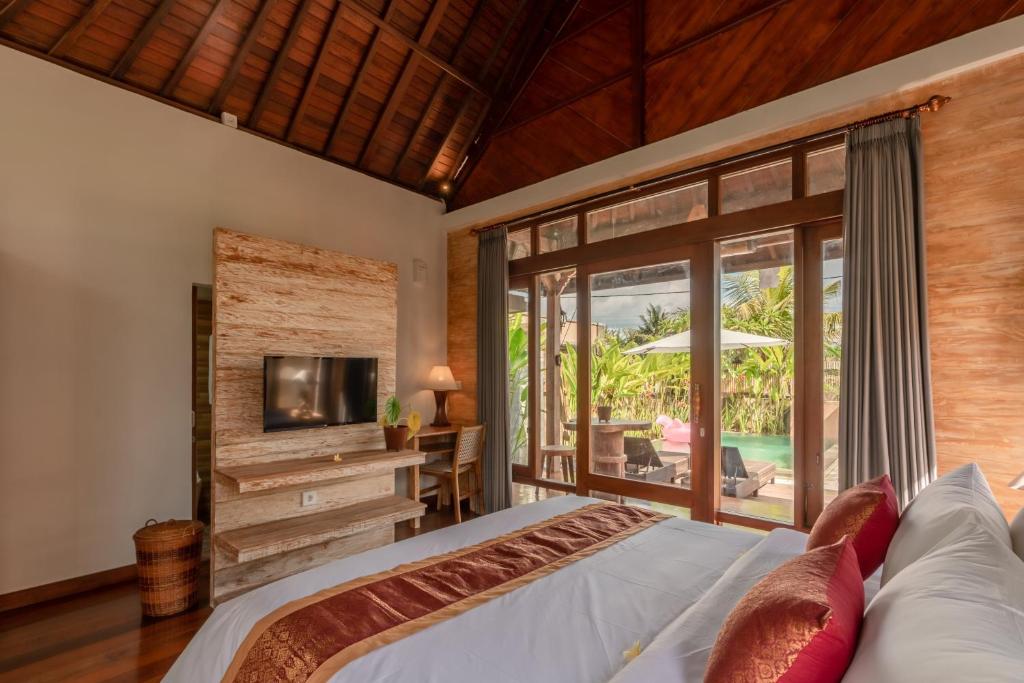 乌布Sridewi Villas Ubud的一间卧室设有一张床、一台电视和一个庭院。