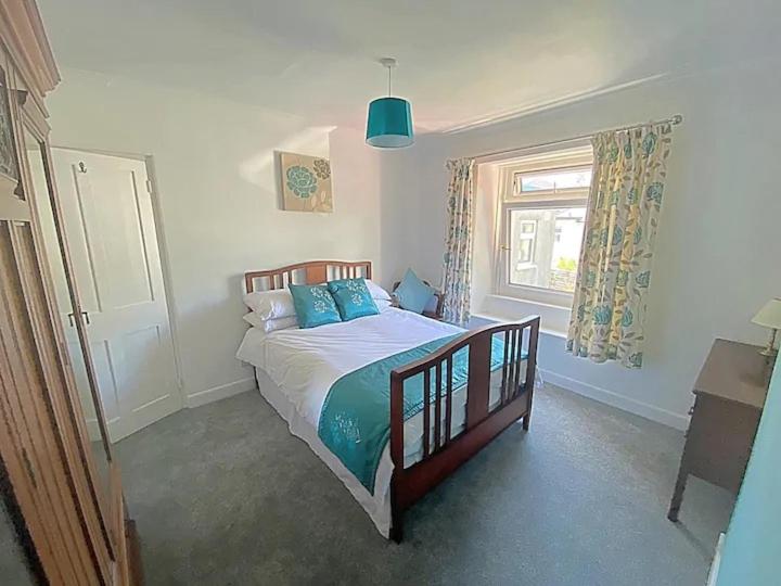 普里茅斯The Retreat @ The Old Smithy, Colebrook Village的一间卧室配有一张带蓝色枕头的床和一扇窗户。