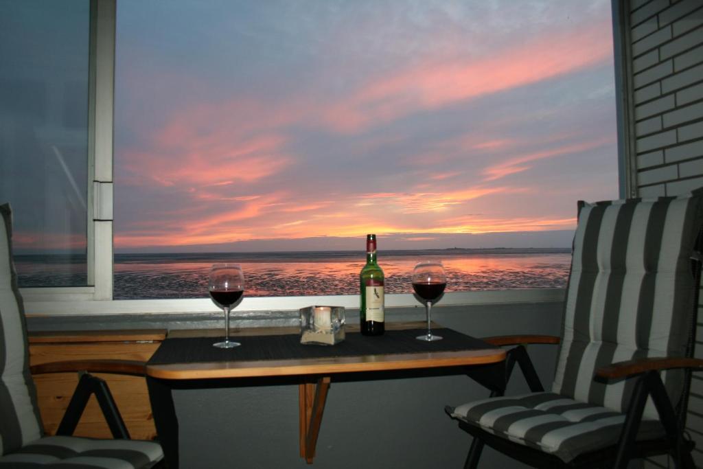 库克斯港Watten-Blick 1的窗户前的桌子上放着一瓶葡萄酒和两杯酒