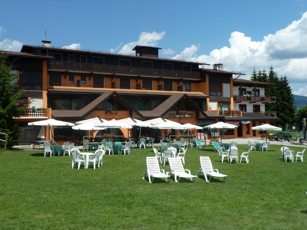 阿夏戈奥博郭米拉蒙提德潘当斯酒店的一座在草地上配有白色椅子和遮阳伞的建筑