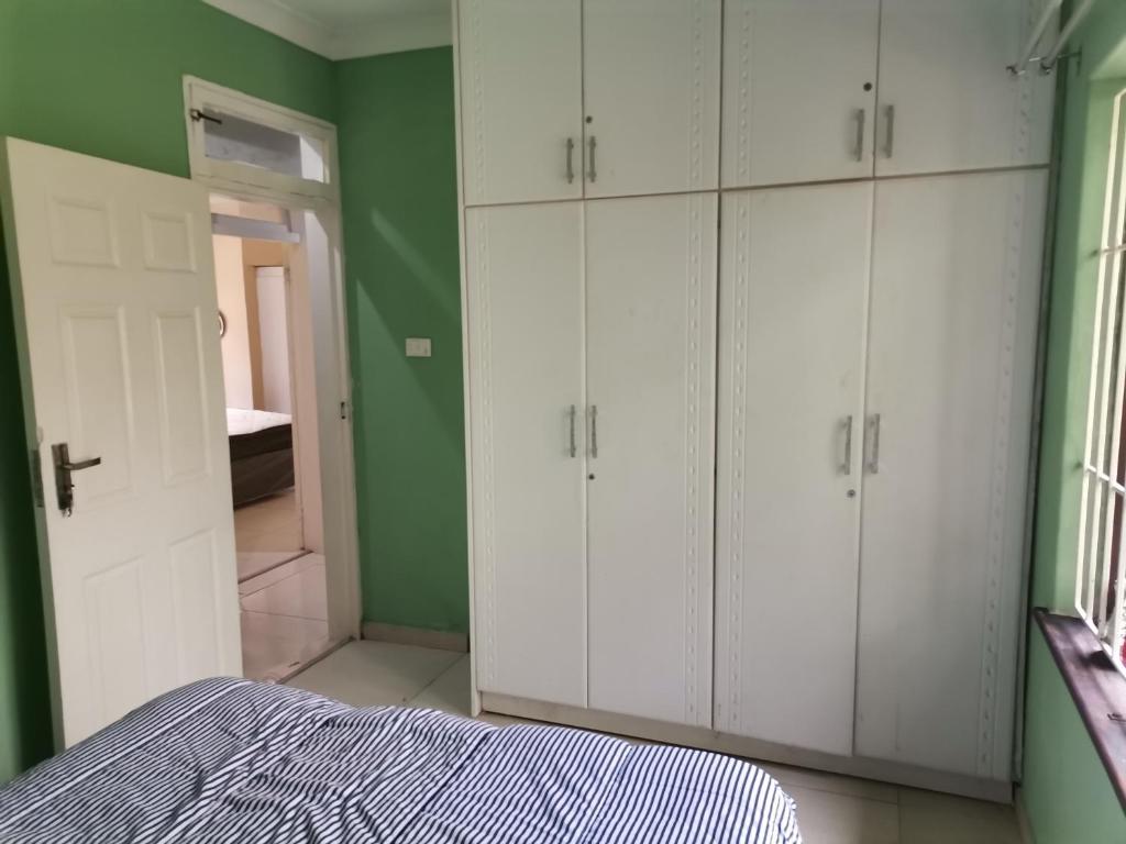 德班Jackies Guest House的卧室配有白色橱柜和绿色墙壁。