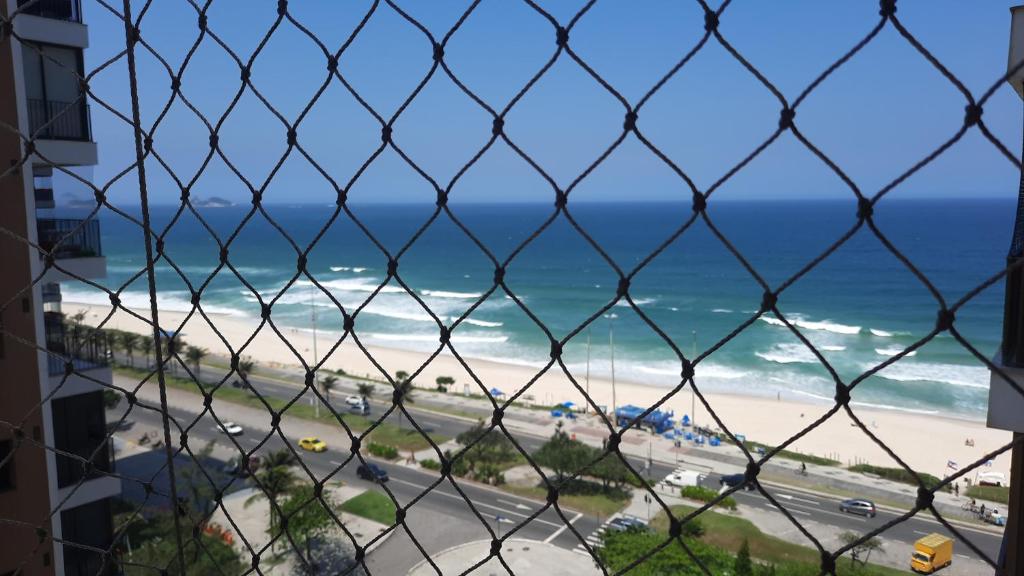里约热内卢Flat 2 suites com vista para o mar e lagoa.的透过链条围栏欣赏海滩景色