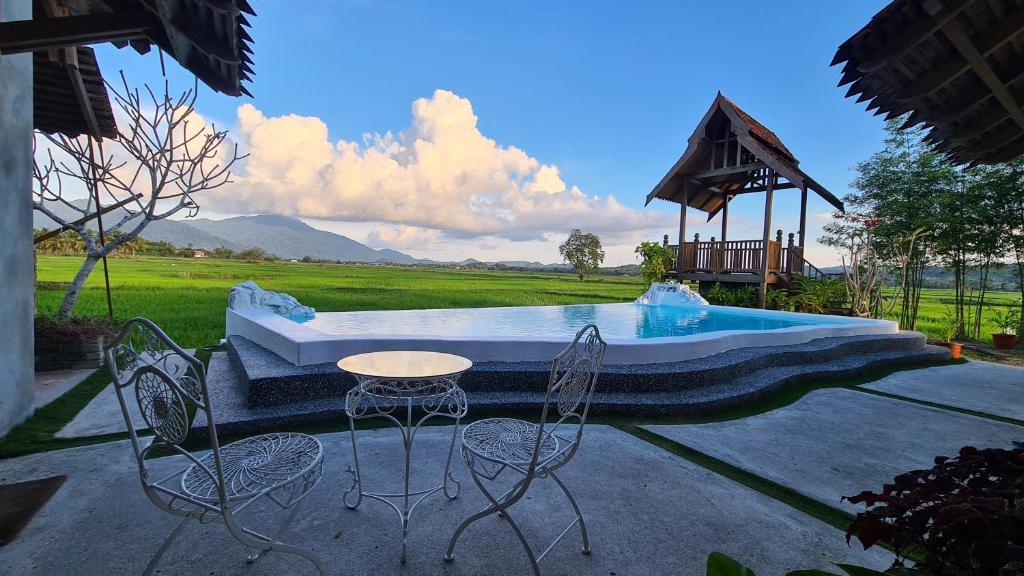 珍南海滩Rumah Bendang Langkawi Villa Pool的池畔露台配有桌椅