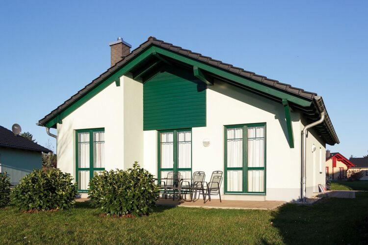 马克莱贝格Holiday home in Markkleeberg near a lake的白色的房子,设有绿色的屋顶,配有桌子和椅子
