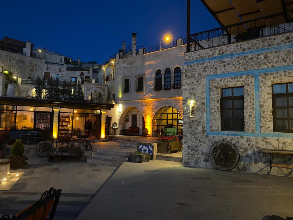 格雷梅卡帕多西亚卡内拉卡威酒店的一座大型石头建筑,晚上设有庭院