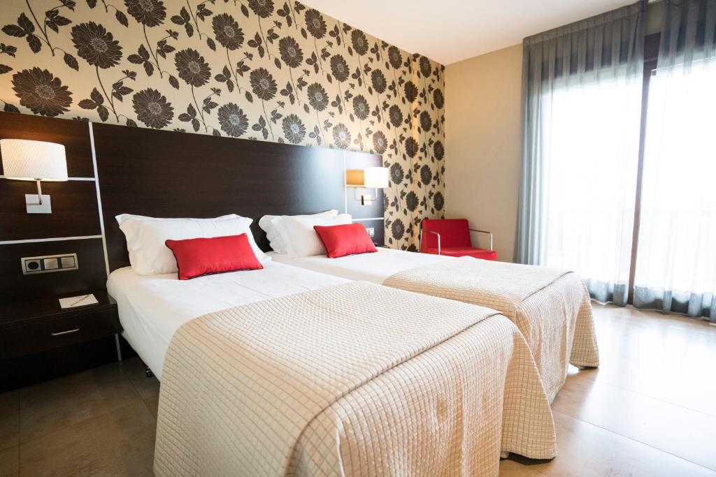 波多诺伏皮拉米德2酒店的两张位于酒店客房的床铺,配有红色枕头