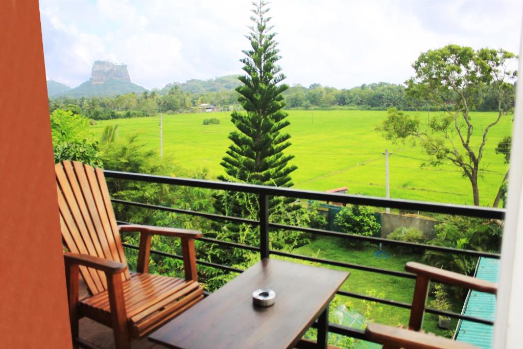 锡吉里亚Sigiriya Water Guest & View Point Restaurant的阳台配有桌椅,享有田野美景。