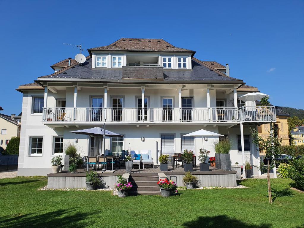 沃尔特湖畔佩莎赫Villa Wieser的带阳台和草坪的大型白色房屋