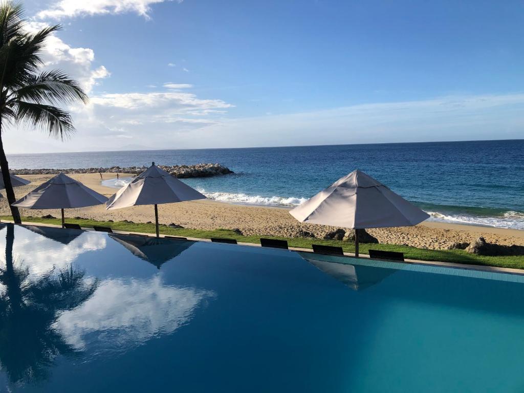 苏莎亚Vacations in the Caribbean Paradise的海滩旁的游泳池,配有遮阳伞