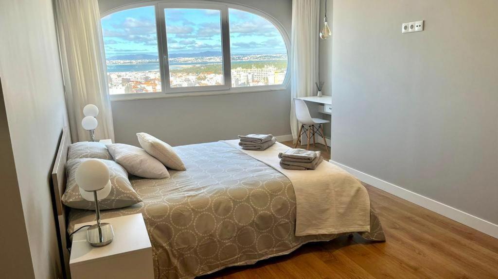 卡帕里卡海岸T2 com uma vista deslumbrante sobre o Atlântico!的一间卧室设有一张大床和大窗户