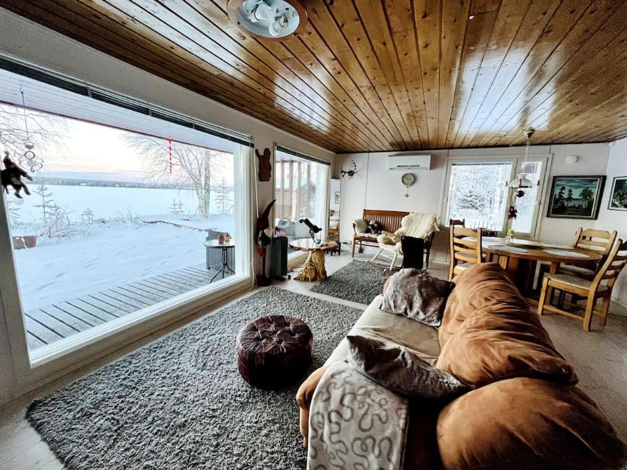 罗瓦涅米Lapland Sunrise Cottage with lakefront Sauna的客厅设有大沙发和大窗户