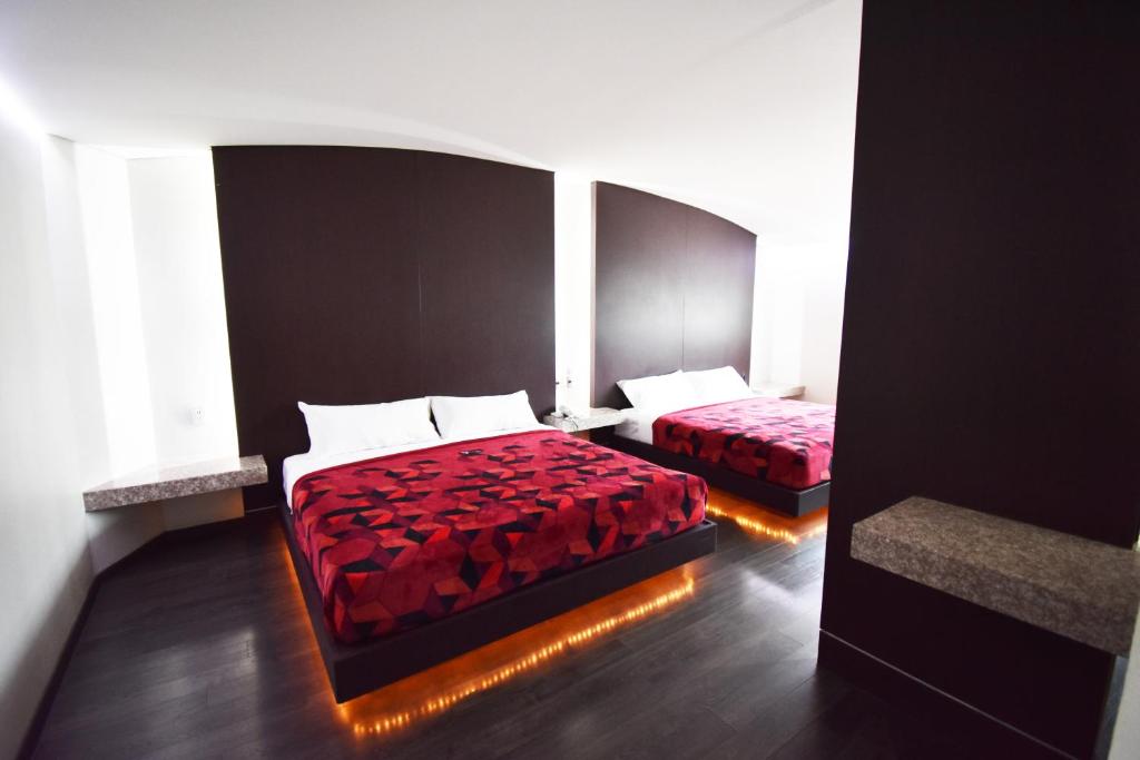 墨西哥城Hotel Via La Villa的一间卧室设有两张红色床罩和窗户。