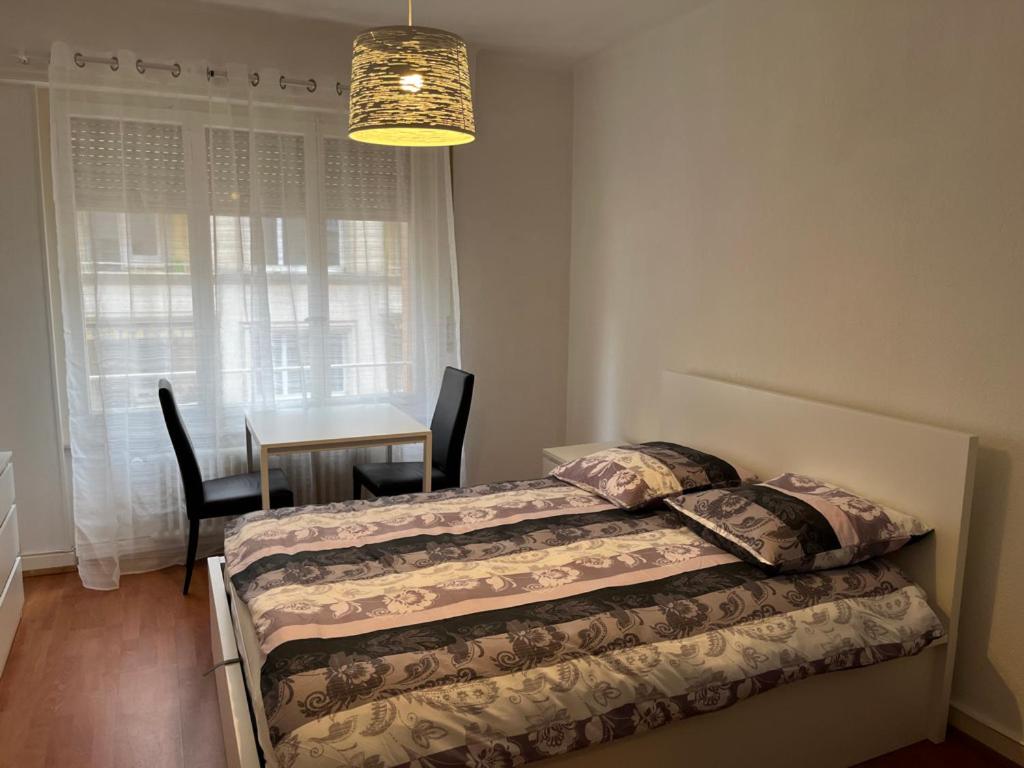 洛桑Gare-20-1的一间卧室配有两张床、一张桌子和一个吊灯。