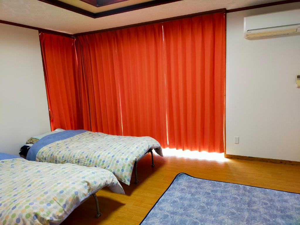 石垣岛碧海白保之宿旅馆的一间卧室配有两张床和橙色窗帘