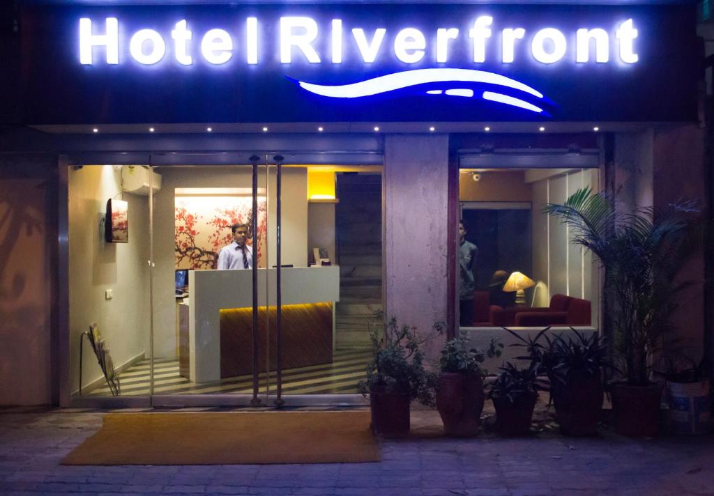 艾哈迈达巴德Hotel Riverfront的夜间在大楼前的建筑标牌