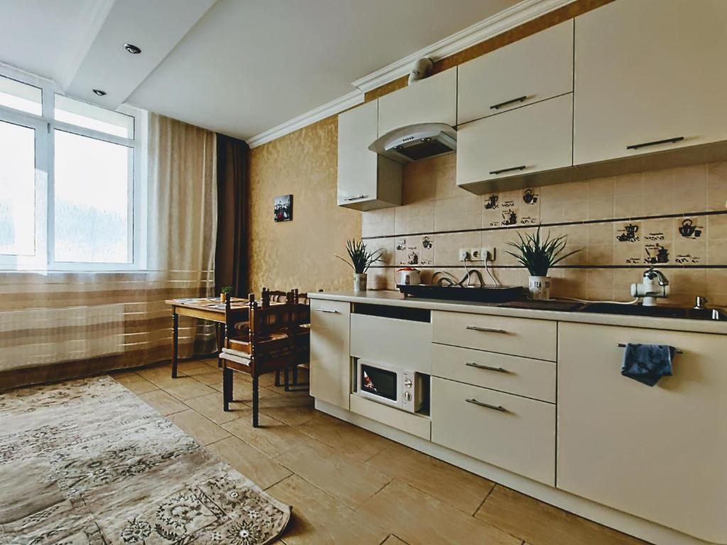 敖德萨Уютная квартира с панорамой города的厨房配有白色橱柜和桌子