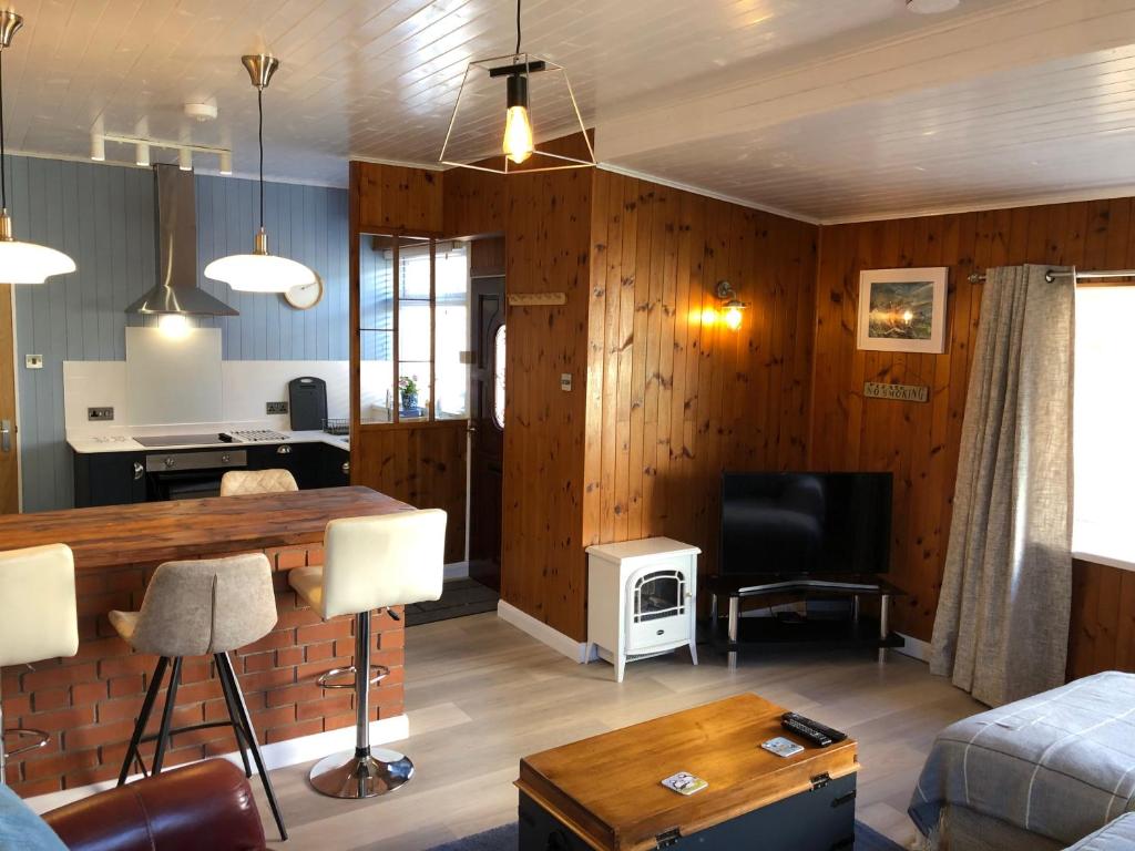 锡豪西斯Little Haven的客厅设有木墙、桌子和电视